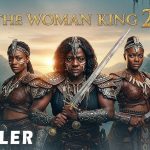 "The Woman King 2 trailer poster with three fierce female warriors holding weapons in a jungle setting at sunset"